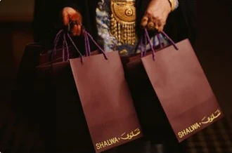 Two burgundy gift bags held by their purple cords