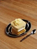 A square cream slice on a black plate