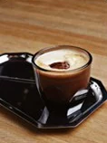 A single espresso on a black tray