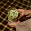A matcha drink held over a checked tray