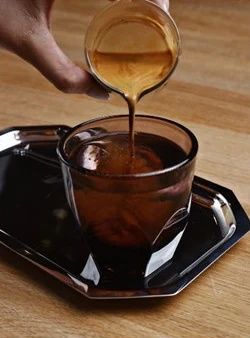 Qahwa poured into a glass cup on a black tray