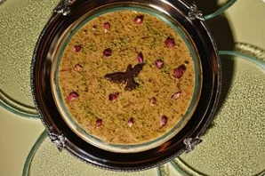 Asida in a silver dish with a chocolate falcon and rose petals