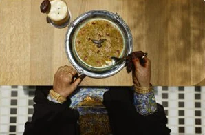 Hands sharing a silver dish on a wooden table