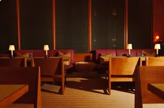 The room: low lamps, wooden tables and a long banquette