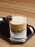 A layered saffron and date drink topped with a date