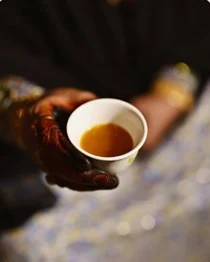 A hand holding a small cup of qahwa